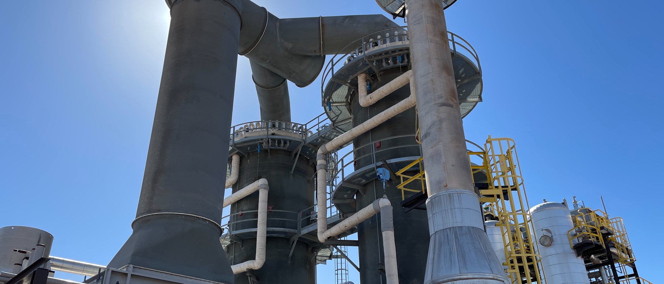 The reformer vessels and their ducting seen from below against a clear sky